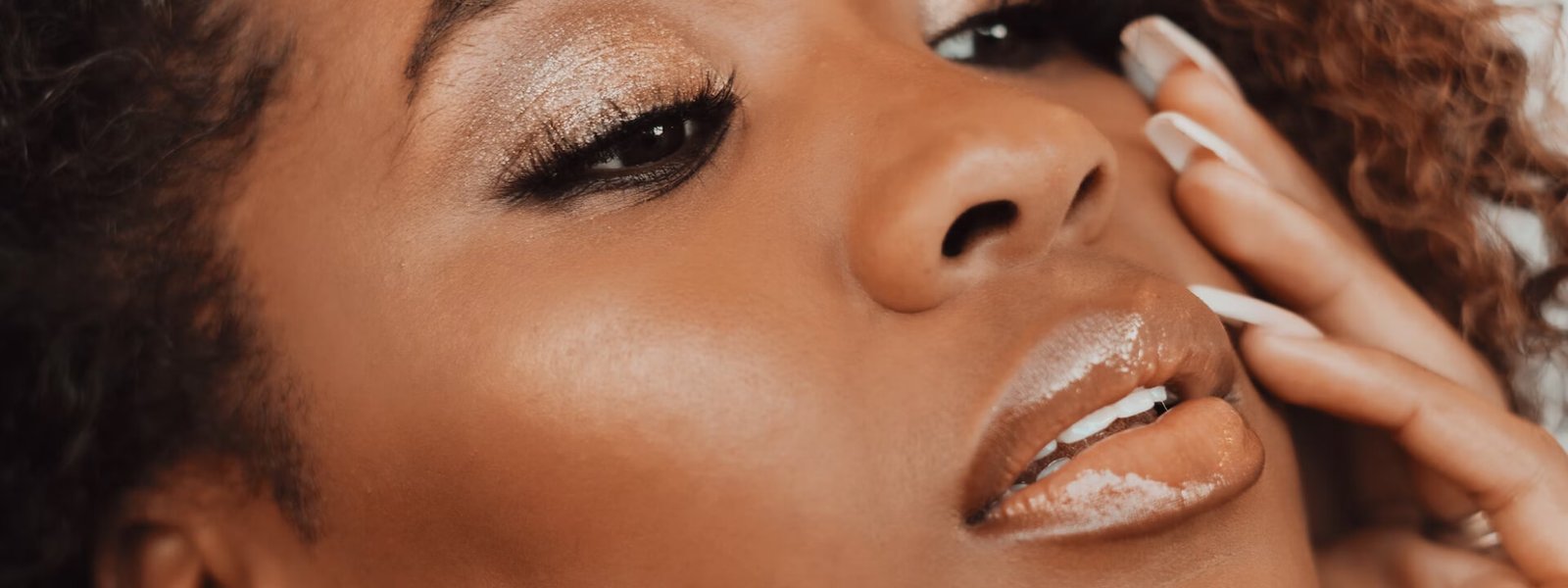 Close-up of a woman with glowing skin and glossy makeup, representing clean skin centric beauty.
